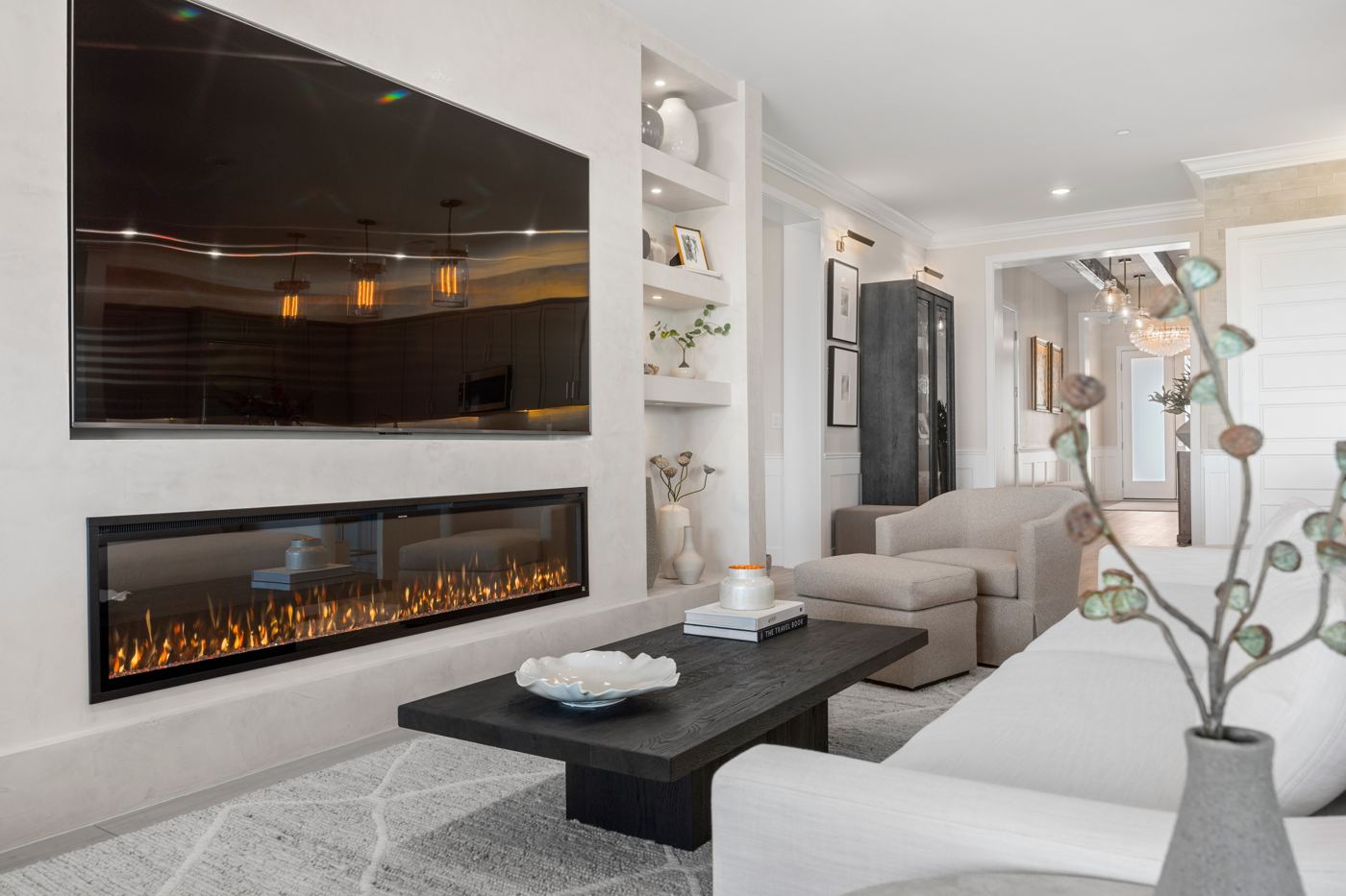 Living room with a long linear fireplace in a plaster wall, a dark oak coffee table, and a cozy swivel chair and ottoman
